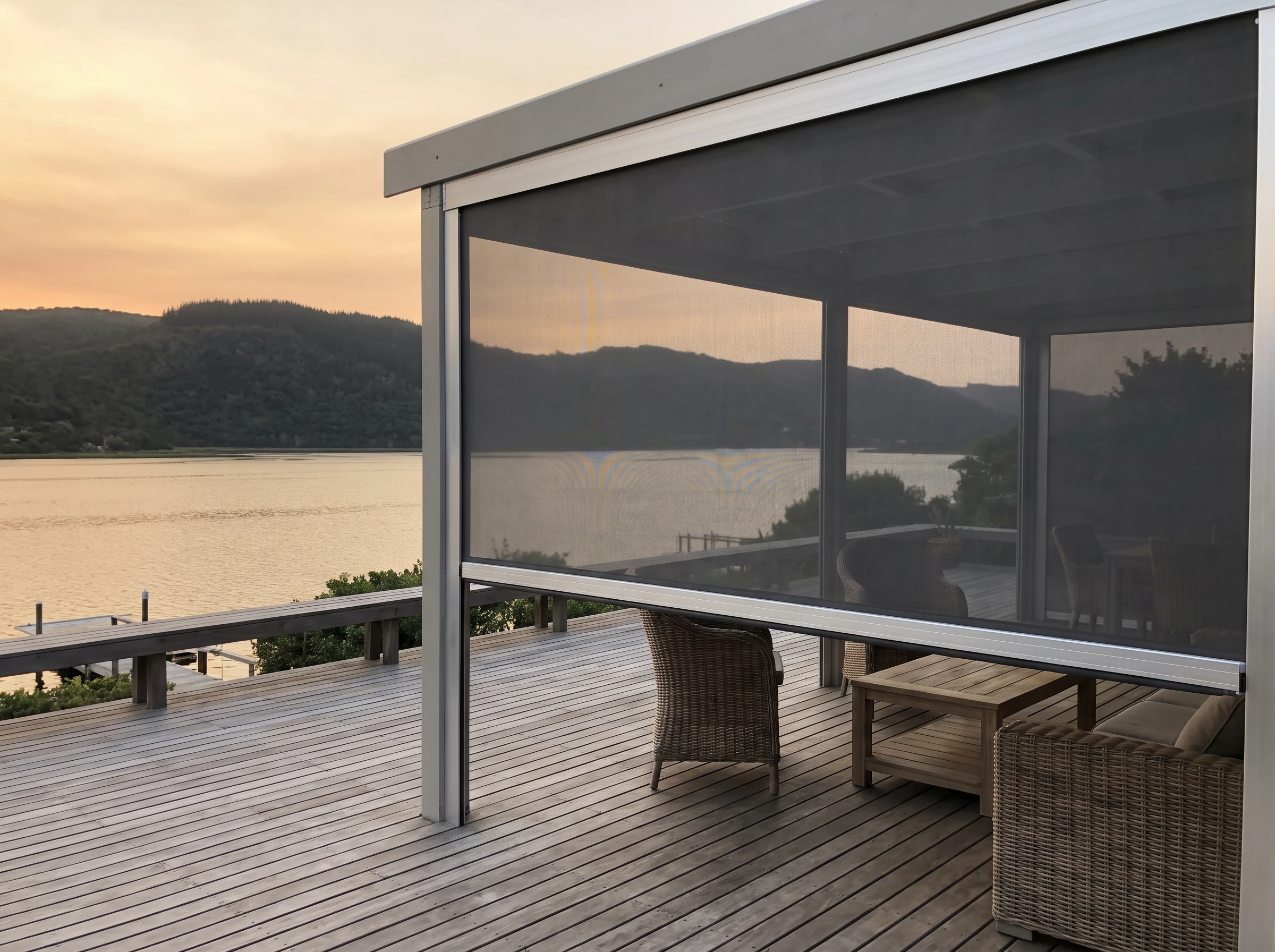 Outdoor zip screen partly lowered in aluminium side channels enclosing a timber deck on the Knysna lagoon in the Garden Route